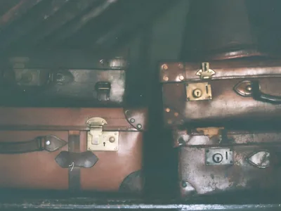 De vieilles valises en cuir empilées dans un grenier sombre, sous la charpente.