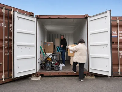 Un box de 33 m³ en cours de chargement : un homme reçoit un carton que lui apporte une femme, à côté de cartons déjà rangés le long de la paroi.