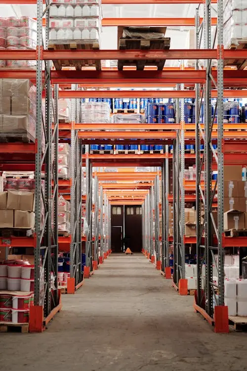 L'allée centrale entre deux rangées de rayonnages chargés de palettes et de cartons.